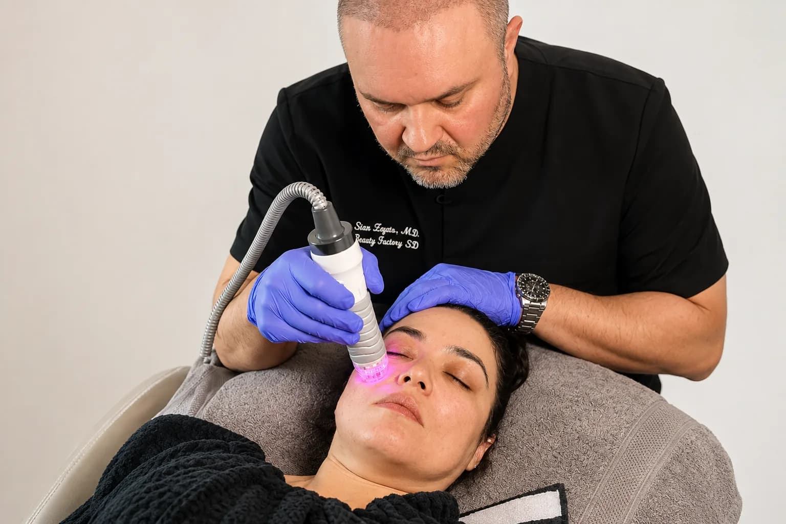 Stanislav Zayets, MD performing a facial treatment on a reclined patient.