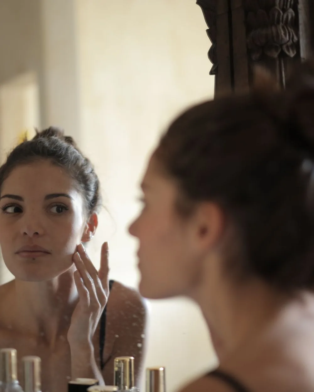 A woman looking at her own face in a mirror.