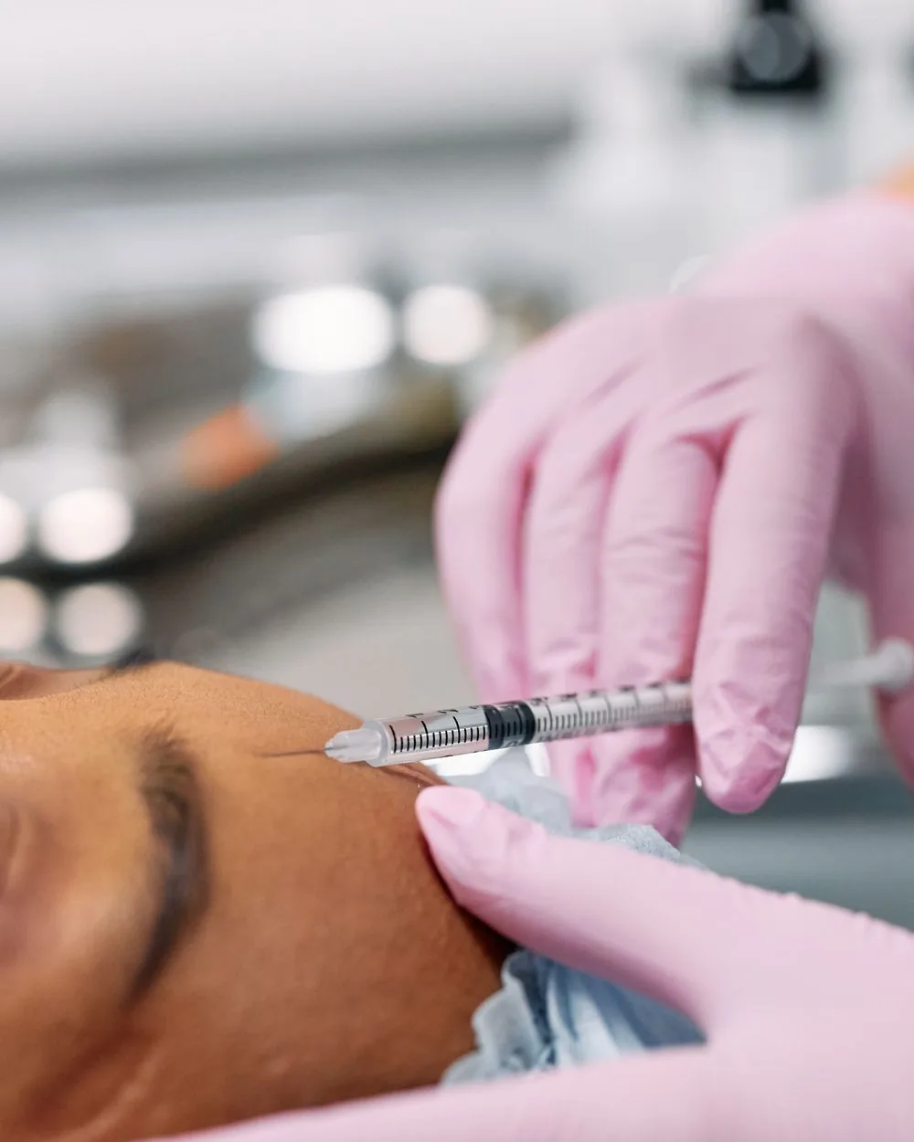 A clinician injecting a wrinkle-relaxing neuromodulator into a patient’s forehead.