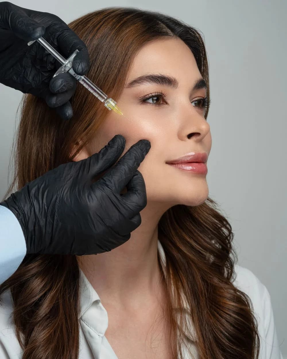 A clinician injecting hyaluronic acid dermal filler into a patient’s face.