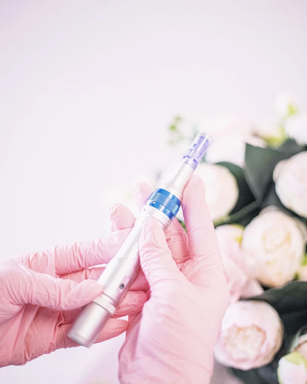 A gloved hand holding a microneedling pen.